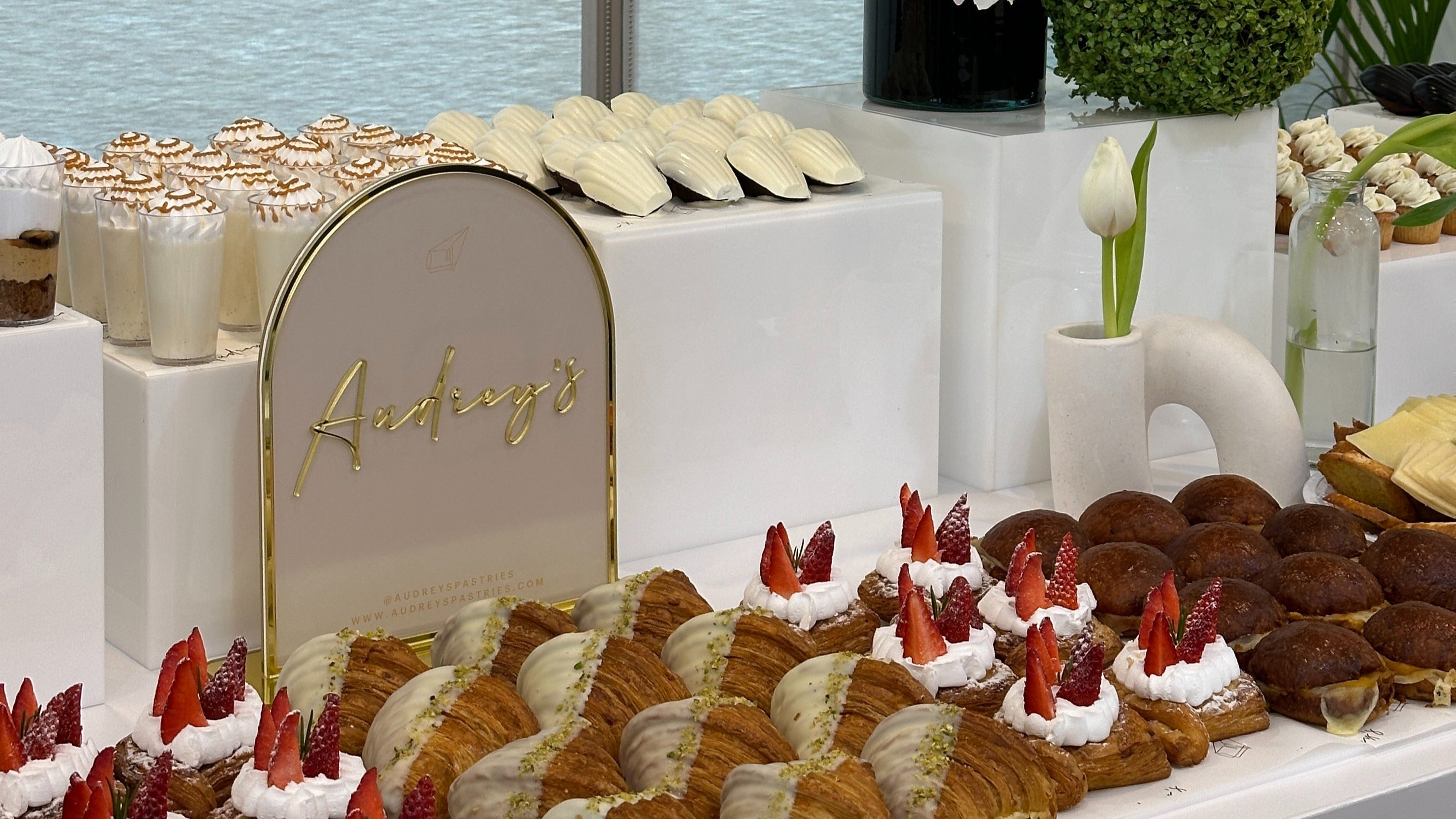 Table with various pastries and a floral arrangement in a modern interior setting.